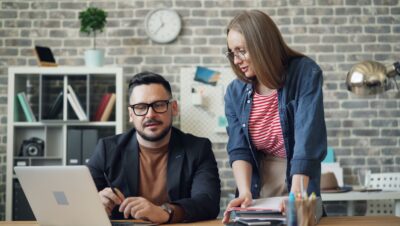 a man and a woman looking at a laptop